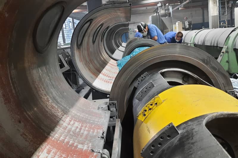 PUR-Mitarbeiter bei der wartungsvorbereitenden Reinigung gro&szlig;er Industriewalzen &mdash; Zugang zu Inspektionspunkten und Schraubverbindungen wird freigelegt.